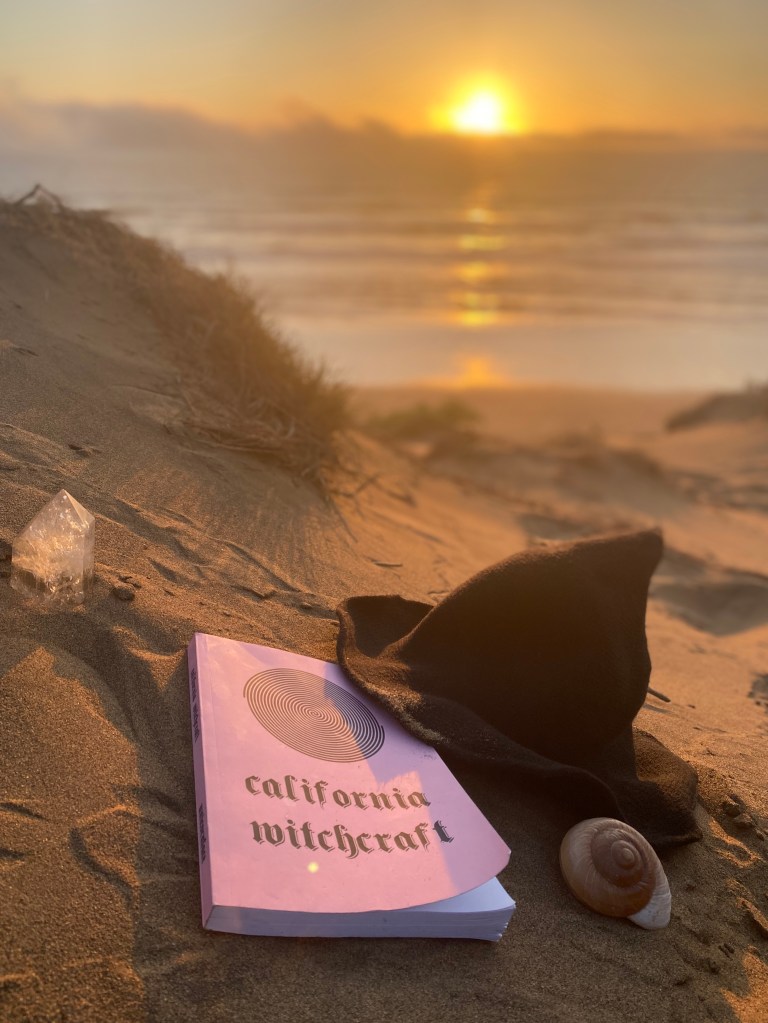 California Witchcraft book and witch hat at sunset on the beach